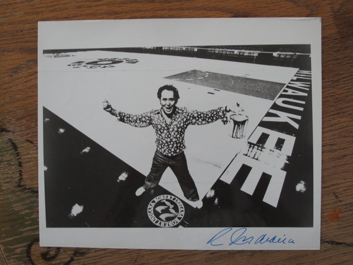 Promotional signed photo of Robert Indiana standing with a paint can on the MECCA floor