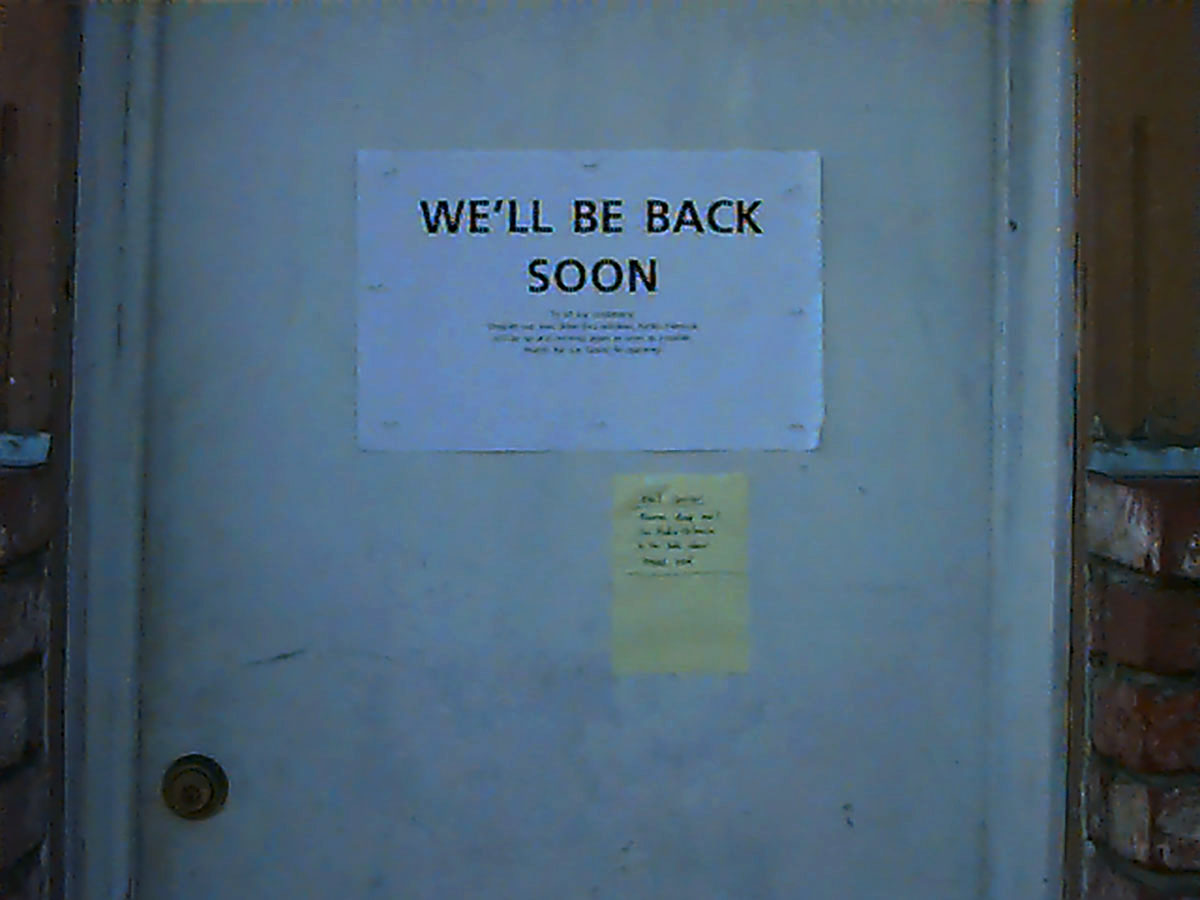 Signs on cafe door; We'll Be Back Soon is the only legible thing